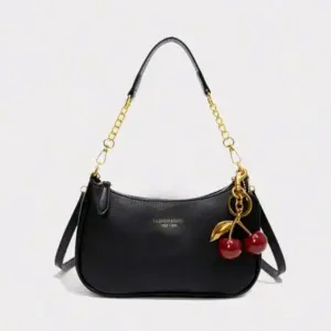 Schwarze Schultertasche mit goldener Kette und Kirschanhänger auf hellem Hintergrund