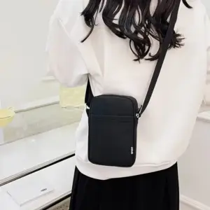 Schwarze kleine Handytasche mit Schulterriemen, von hinten über der Schulter getragen
