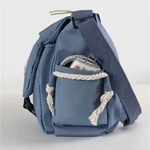 Blaue Messenger-Tasche aus Stoff in Seitenansicht mit Seitentasche und breitem Gurt