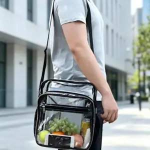 Transparente Umhängetasche mit schwarzen Rändern, gefüllt mit Obst und Smartphone, getragen